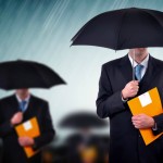 Businessman with umbrellas in heavy rain.