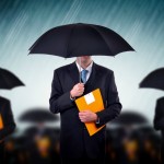 Businessman with umbrellas in heavy rain.
