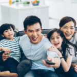Cheerful asian family watching tv together