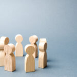 People stand in a circle on a gray background. Wooden figures of people. A circle of people. discussion, cooperation, cooperation. Communication. Business team, teamwork, team spirit. Selective focus